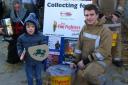 Youngster Dylan Clift makes a donation at Ludlow’s medieval fair alongside firefighters Andrew Jones and Richard Clarke (kneeling).