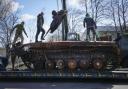 Road workers load a destroyed Russian tank onto a platform in the village of Andriyivka close to Kyiv, Ukraine, Monday, Apr. 11, 2022. Andriyivka was occupied by the Russian troops at the beginning of the Russia-Ukraine war and freed recently by the