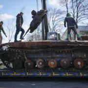 Road workers load a destroyed Russian tank onto a platform in the village of Andriyivka close to Kyiv, Ukraine, Monday, Apr. 11, 2022. Andriyivka was occupied by the Russian troops at the beginning of the Russia-Ukraine war and freed recently by the