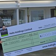 David Bryan Jones, manager of Halls’ Bishops Castle office, presents a cheque for £1,000 to Kate Evans, Bishops Castle & District Community Land Trust chair, outside the building that is being renovated and converted into two flats and a pop up shop.