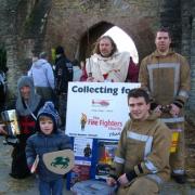 Youngster Dylan Clift makes a donation at Ludlow’s medieval fair alongside firefighters Andrew Jones and Richard Clarke (kneeling).